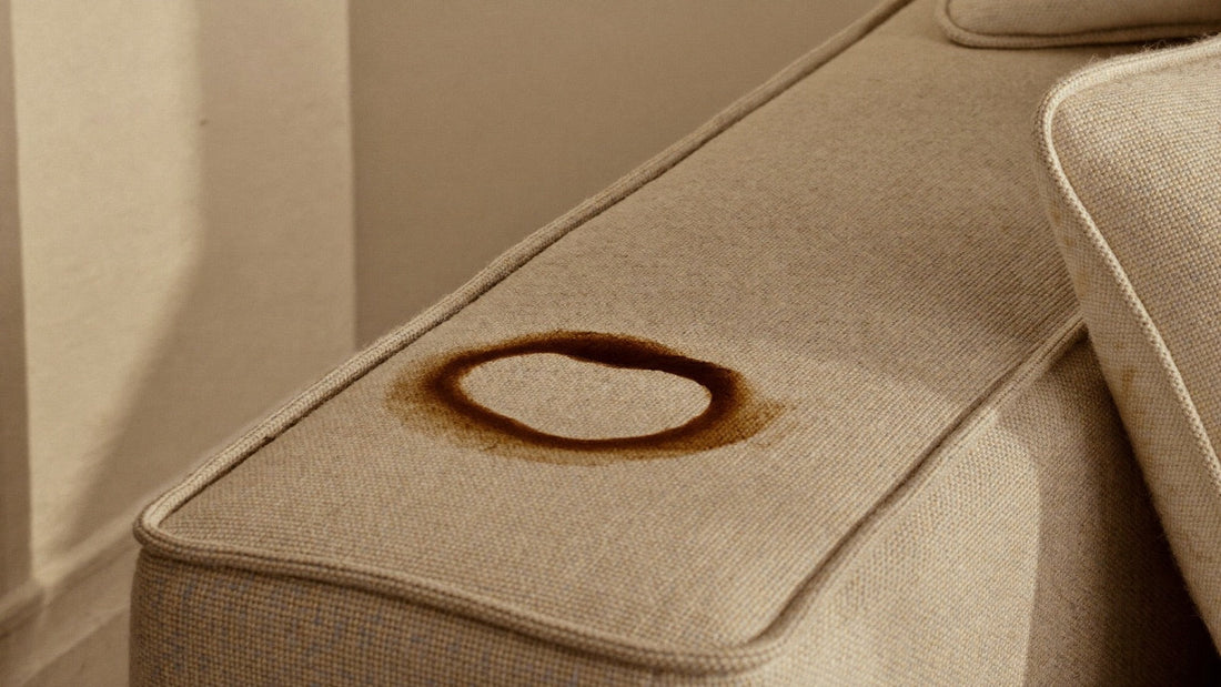 Mancha de café en el brazo de un sofá de tela beige